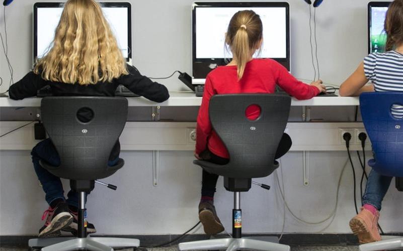 Schülerinnen arbeiten in einem Klassenraum einer Grundschule an Computern. Foto: Friso Gentsch/dpa