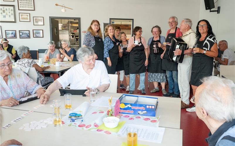 Ausstaffiert mit Schürzen – die Ehrenamtlichen des DRK-Bistros (von links): Heike Liebendörfer, Ulrike Holzner, Hertha Harms, Birgitta Lutz, Carmen Neuffer, Monika Gindorf, Bernd Mutz, Herbert Häcker mit dem Akkordeon und Carmen Koebe (Leitung). GB-Foto: Vecsey