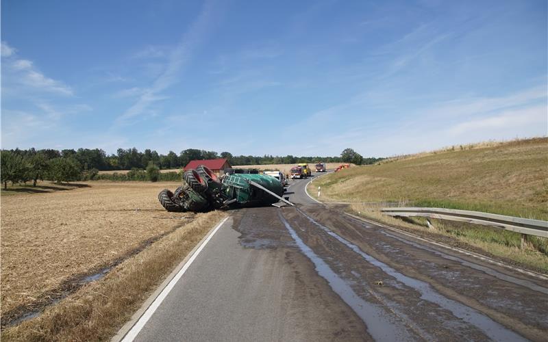 Traktor und Anhänger kippen um, Gülle fließt auf Straße und Felder